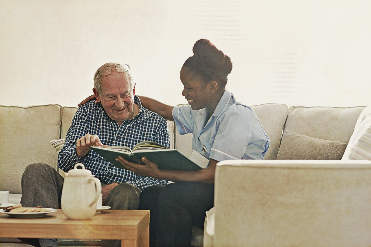 caregiver reading book with elderly client